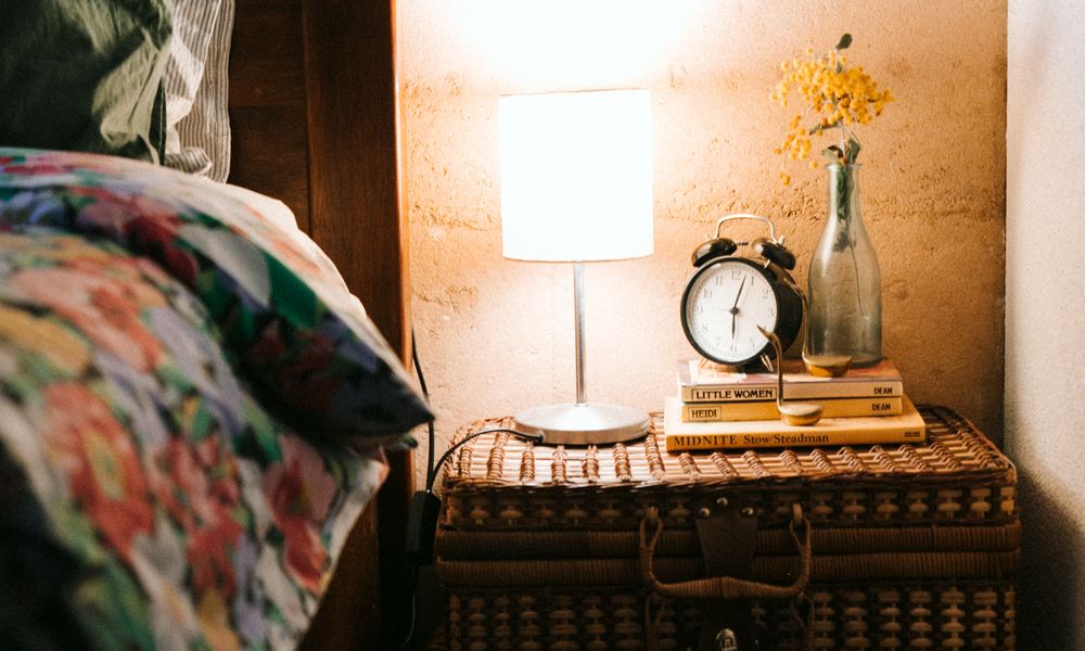 A neatly made bed in a dimly lit bedroom bathed in warm, low light at night